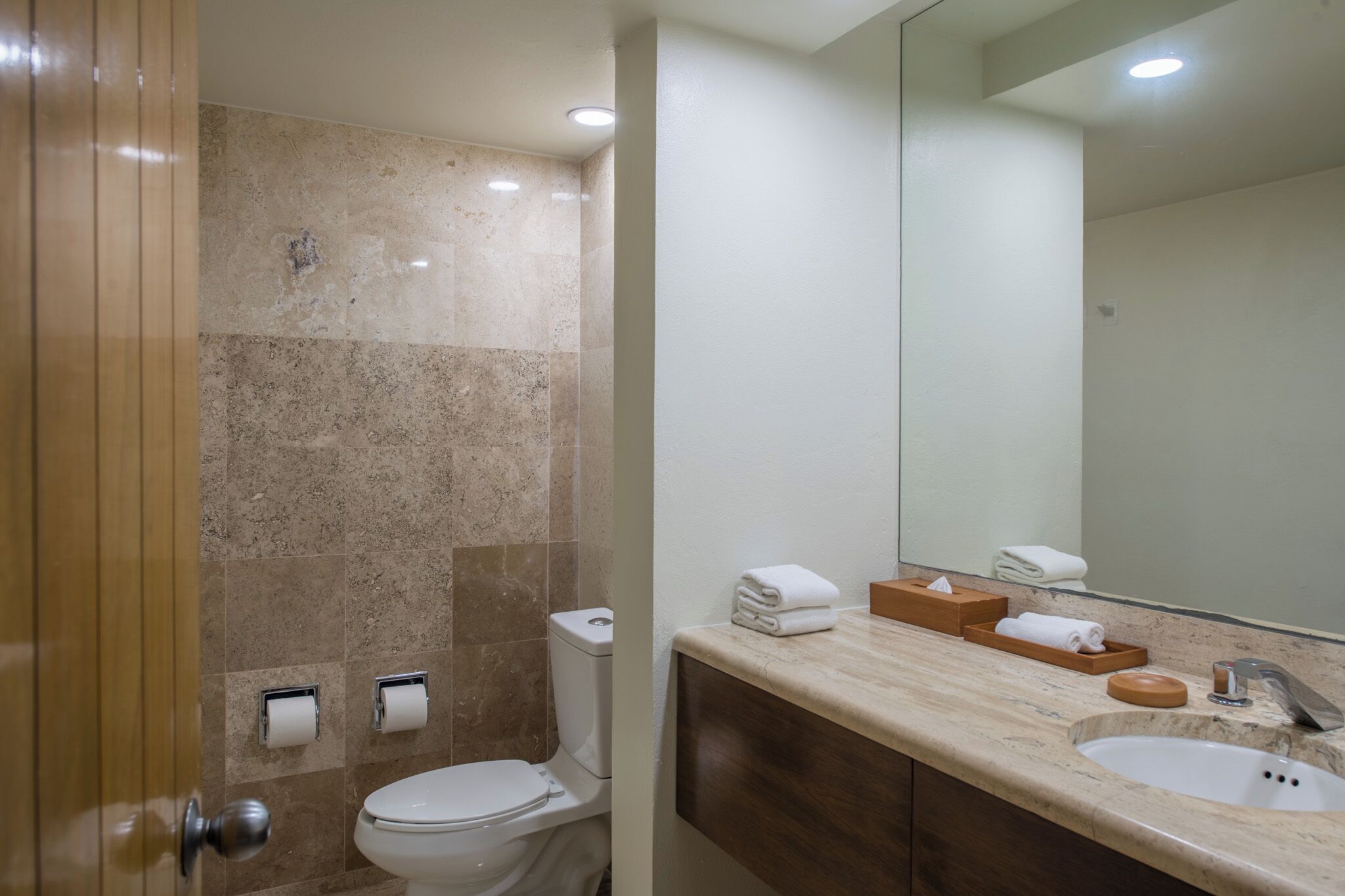 A modern bathroom with a marble sink, a toilet, and a mirror.