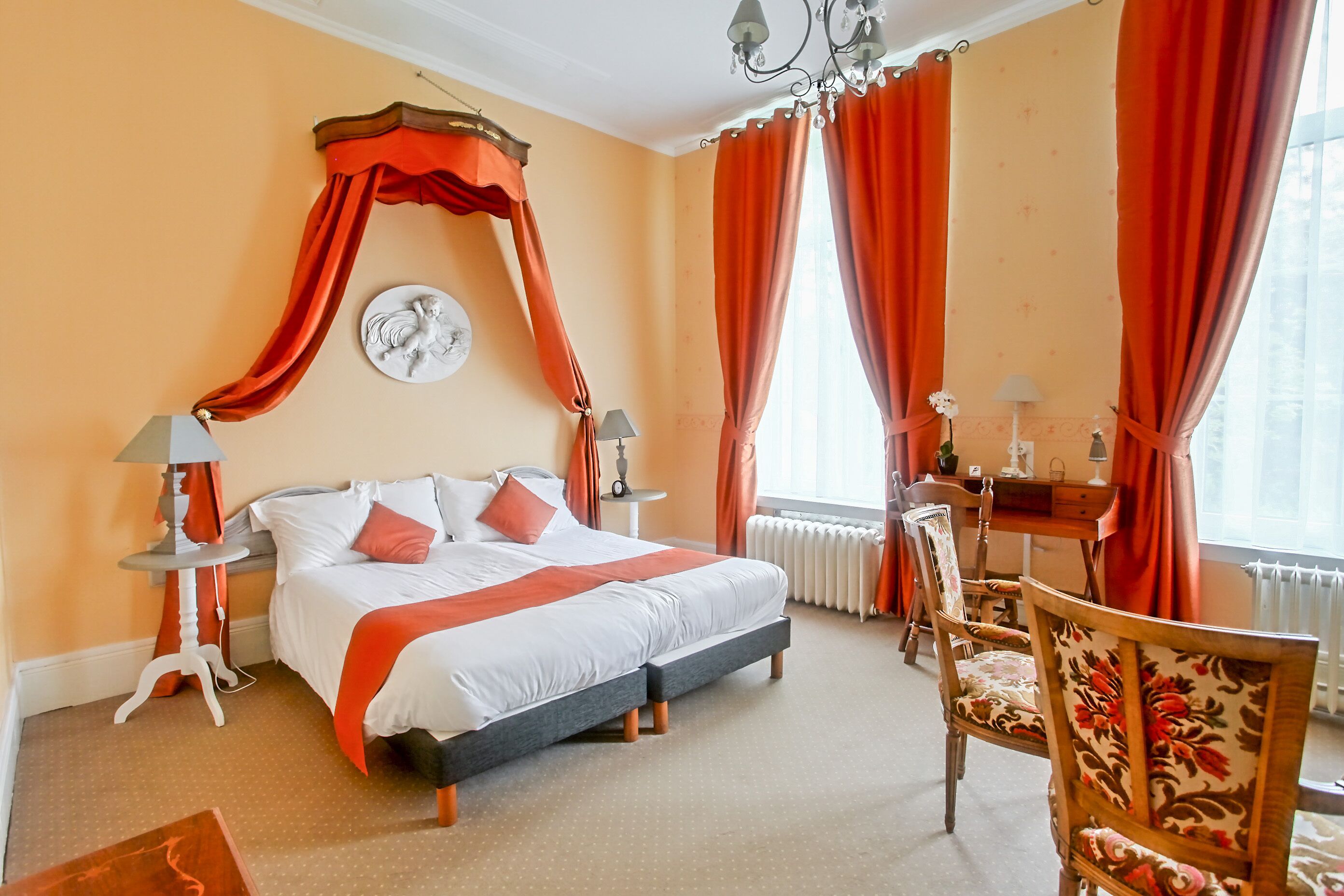A hotel room with a large bed, a desk, and a chair.