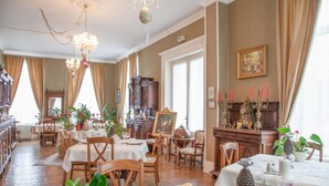 Une salle à manger avec des meubles en bois, un lustre et un piano.