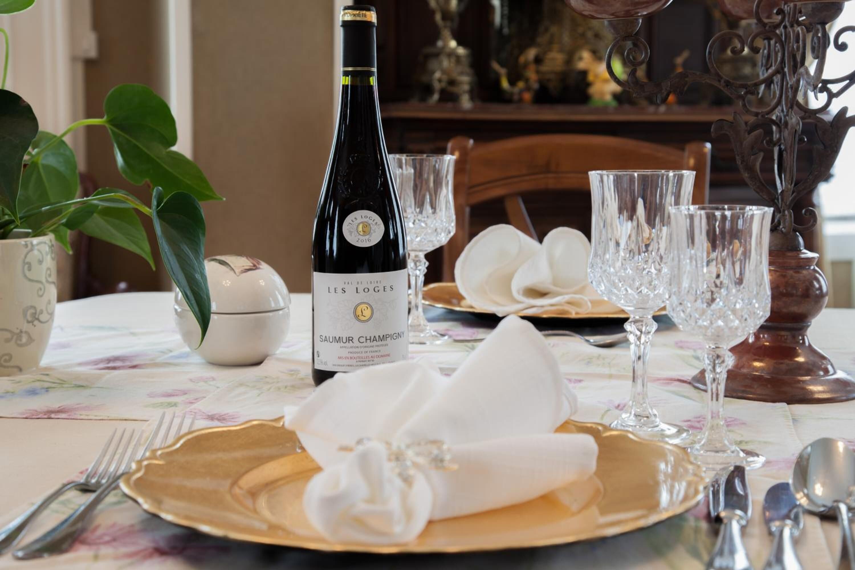A dining table set with a bottle of wine, plates, and cutlery.