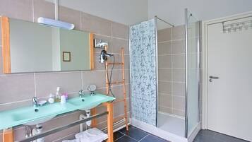 Baño con lavamanos de vidrio, espejo y ducha con escalera de bambú.