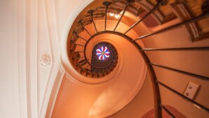 Un escalier en colimaçon surmonté d’une fenêtre à vitraux.