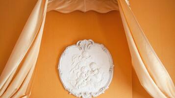 Una cama con dosel, almohadas blancas y un adorno en la pared.