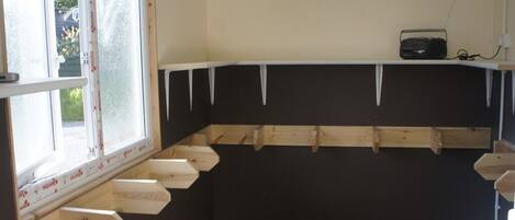 A room with a window, a wooden shelf, and a green carpet.