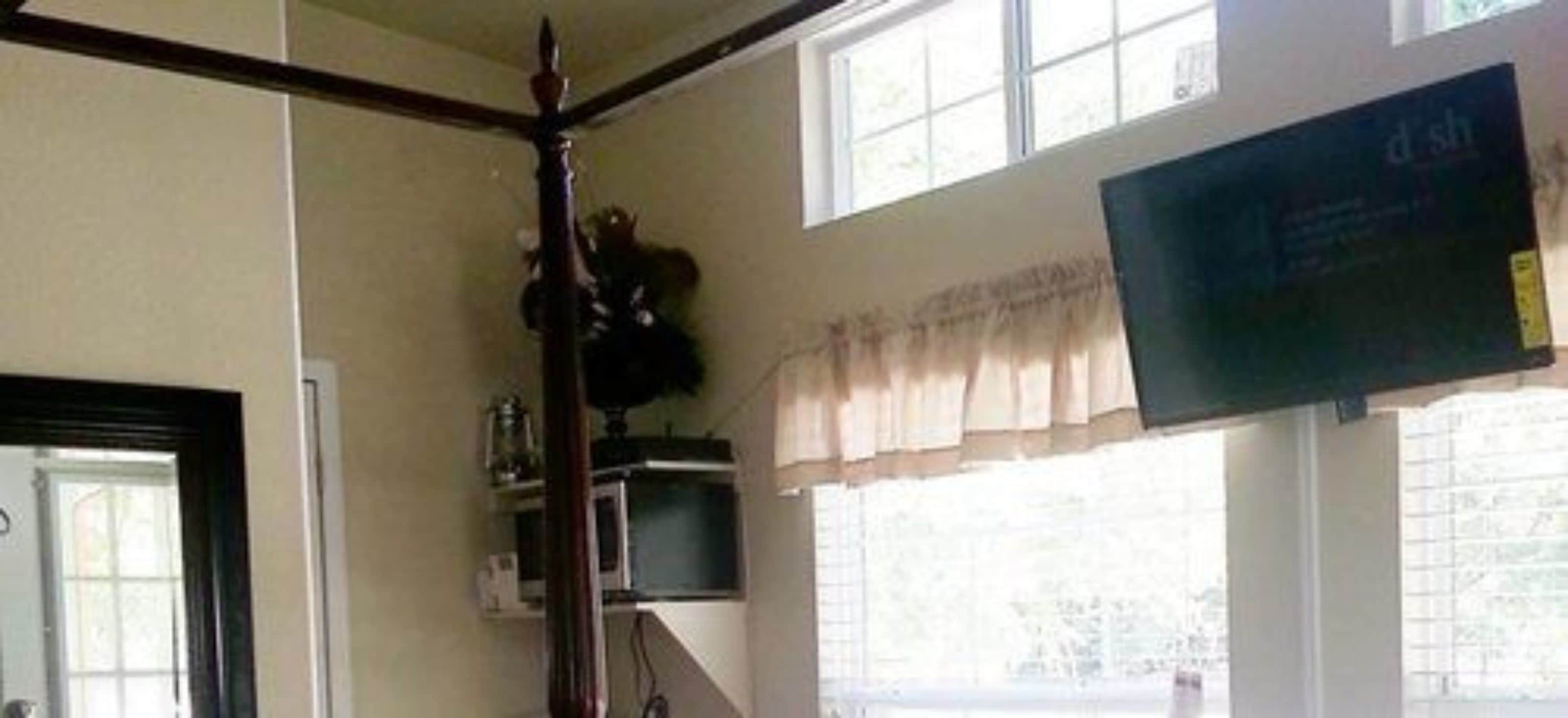 A room with a large window, a flat-screen TV mounted on the wall, and a wooden chair.