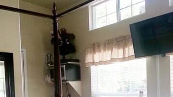 A room with a large window, a flat-screen TV mounted on the wall, and a wooden chair.
