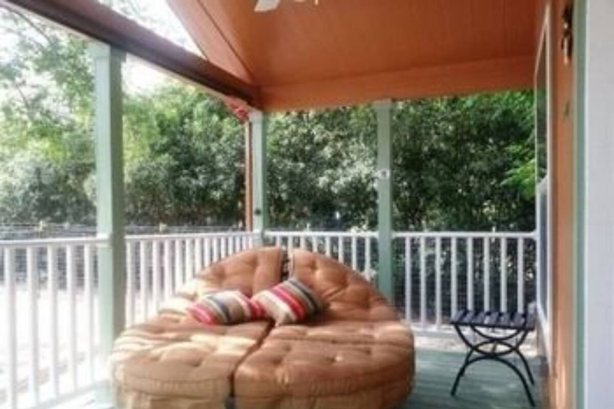A covered outdoor seating area with a cushioned bench and a small table.