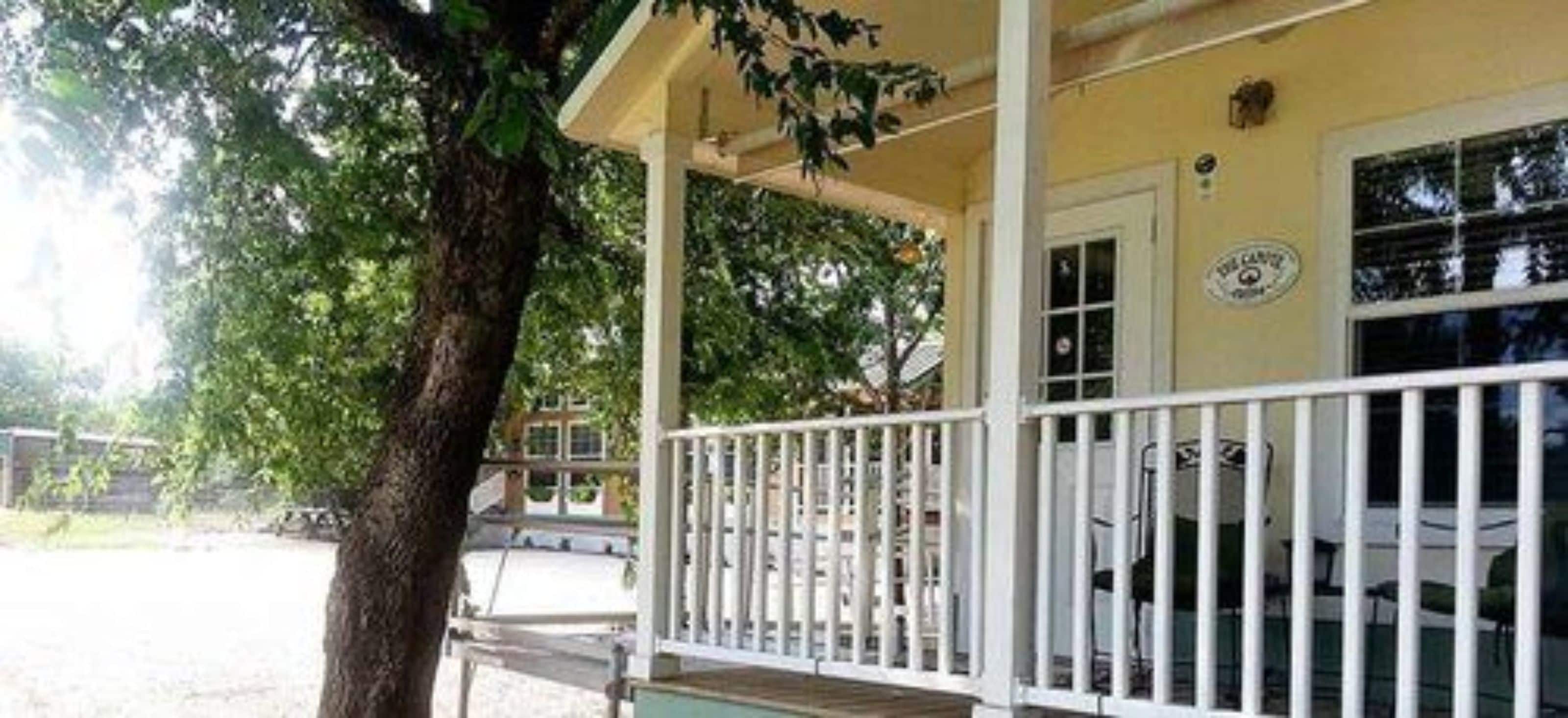 A building with a porch, a tree, and a window with a sign.