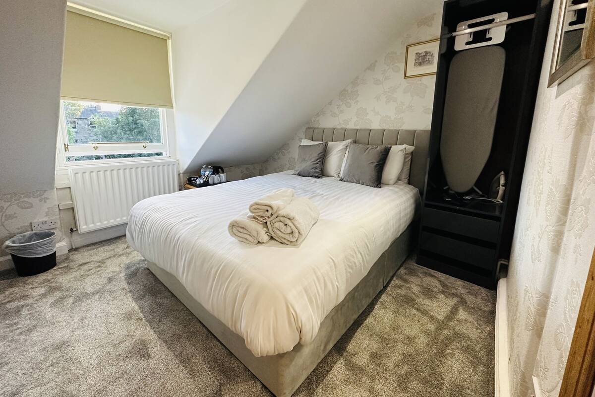 A bedroom with a bed, a radiator, a window, and a mirror.