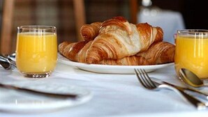 A breakfast setting with croissants and orange juice on a white table. - Abbotsford Guest House (Edinburgh)