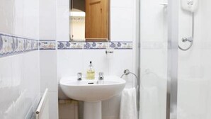 A bathroom with a white sink, a mirror, a shower, and a wooden floor. - Abbotsford Guest House (Edinburgh)