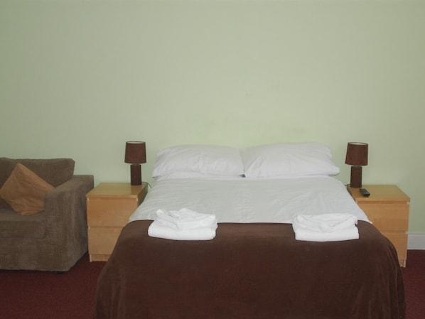 A neatly made bed with white linens, two bedside lamps, a brown blanket, and a brown pillow on a wooden nightstand. - Falcons Nest (Huntingdon)