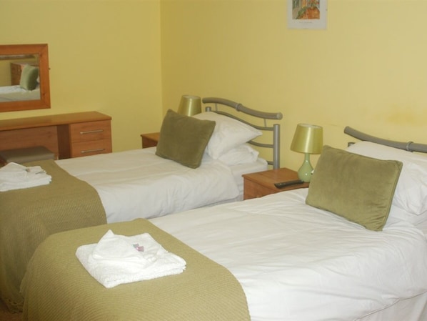 A hotel room with two single beds, each with a pillow and a bedside table with a lamp. - Falcons Nest (Huntingdon)