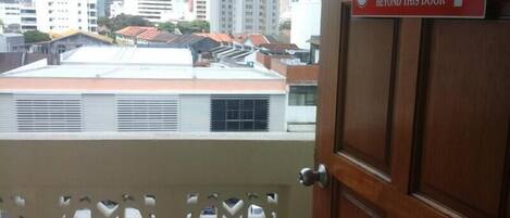 A view of a cityscape through a window with a sign indicating a designated smoking area beyond the door.