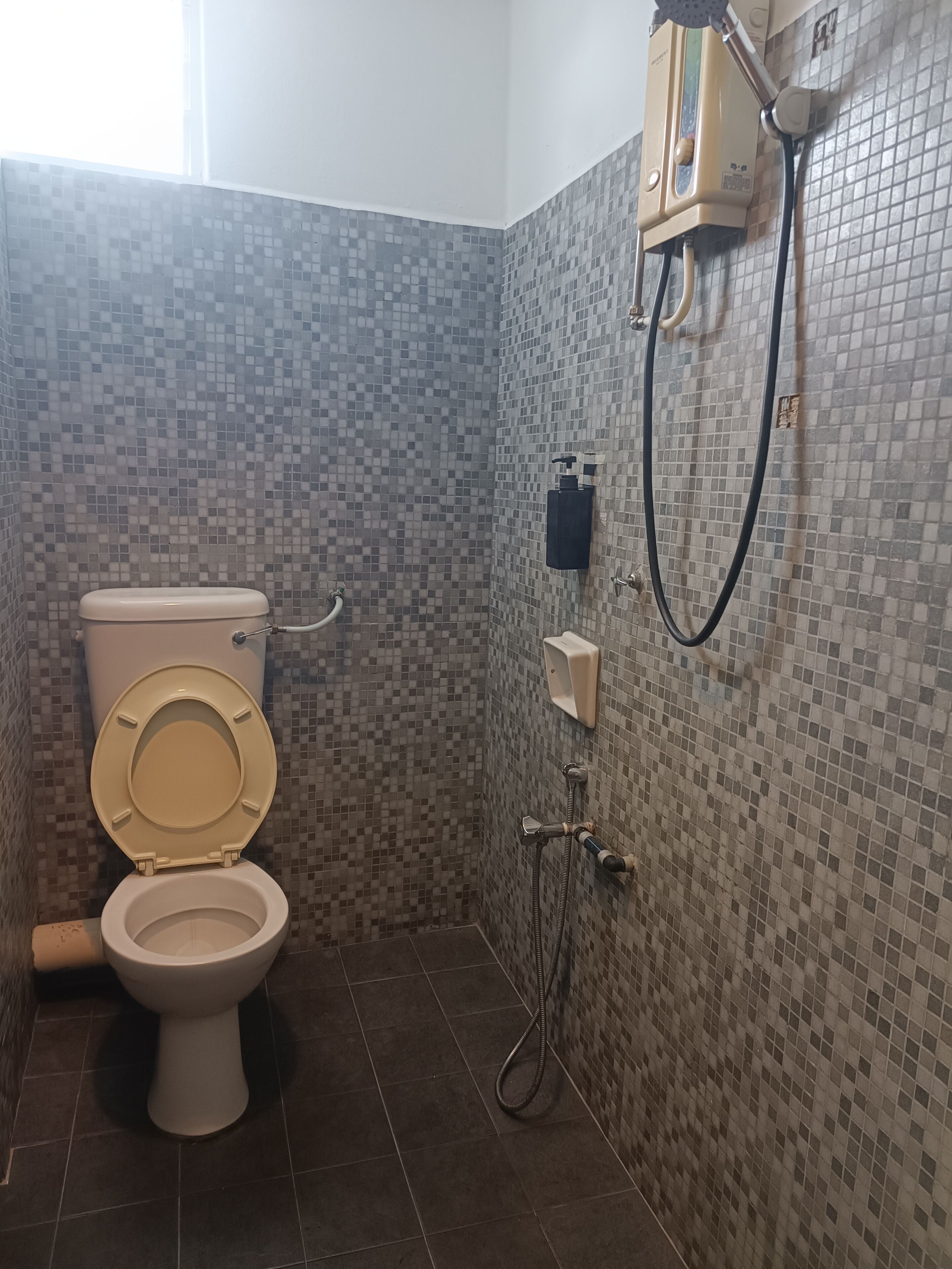 A bathroom with a toilet, a shower unit, and tiled walls.