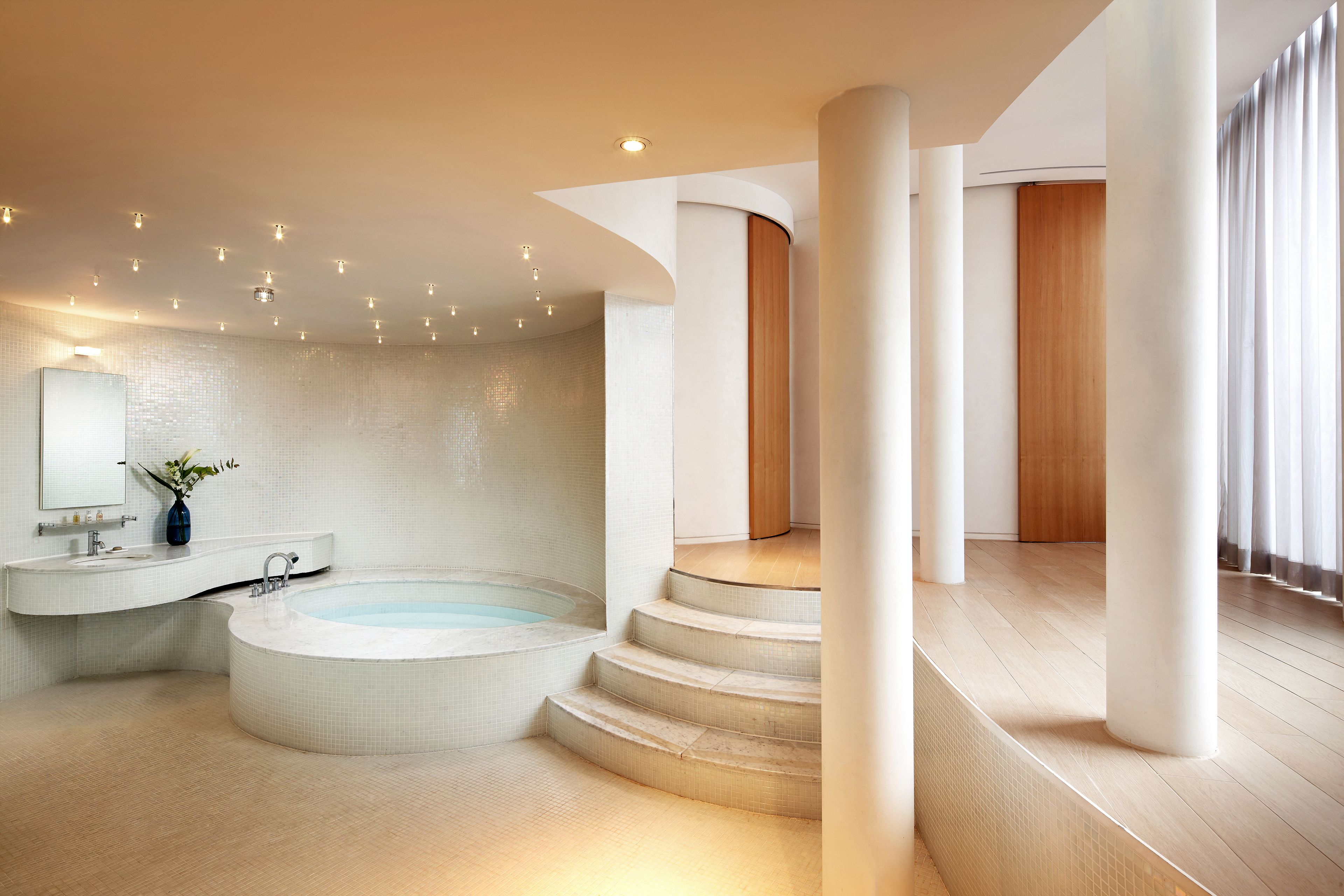 A modern bathroom with a freestanding bathtub, a vanity with a mirror, and a wooden door.
