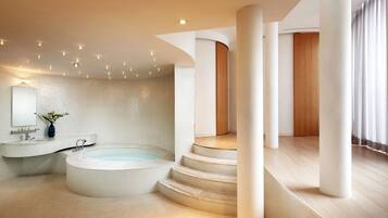 A modern bathroom with a freestanding bathtub, a vanity with a mirror, and a wooden door.