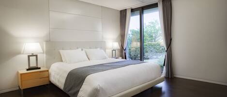Habitación de hotel moderna con una cama grande, mesitas de noche y vistas a zonas verdes.