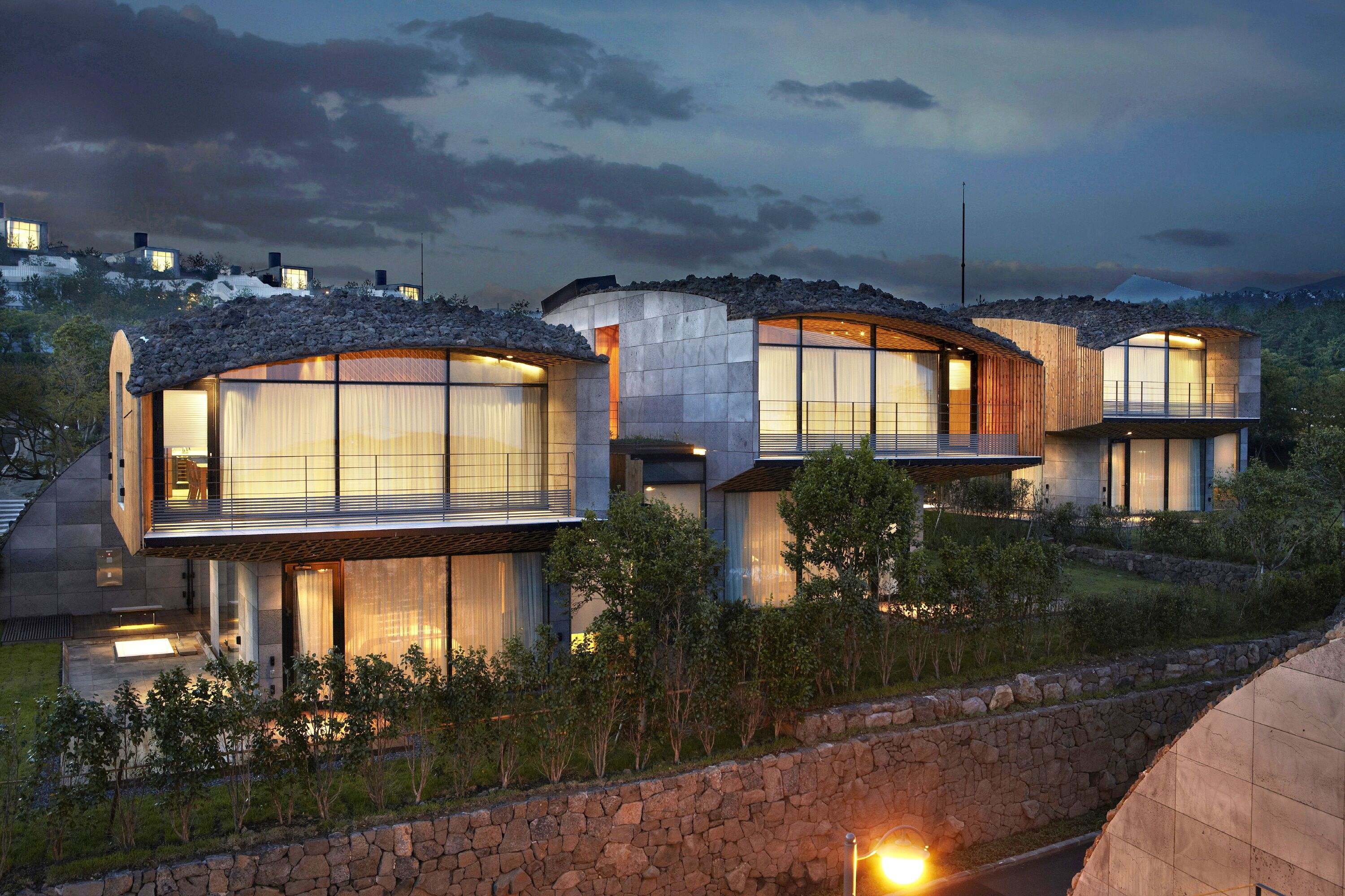Un edificio residencial moderno de varios pisos, con grandes ventanales y fachada de piedra.