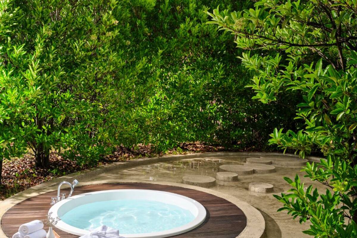 A hot tub surrounded by a wooden deck and lush greenery.