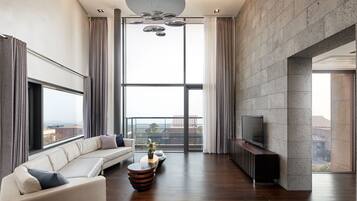 A modern living room with a large window, a sofa, a coffee table, and a flat-screen TV.