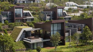 Un complejo residencial moderno con varios edificios que destacan por sus grandes ventanales, techos planos y algunos con cubiertas ajardinadas.