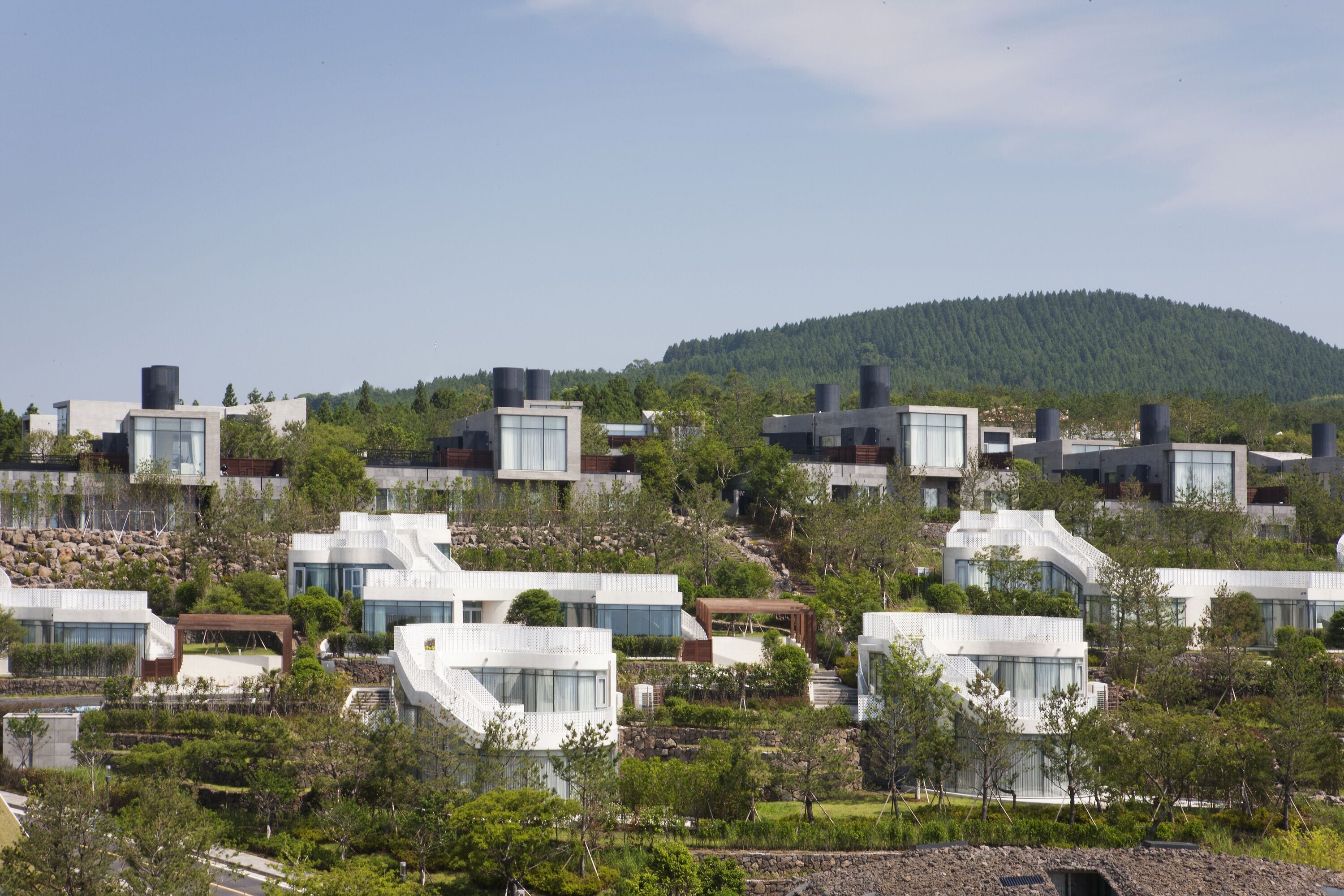 A residential area with modern houses, a hillside, and a clear sky.