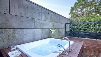 Un área de spa con hidromasaje, terraza de madera y pared de hormigón.