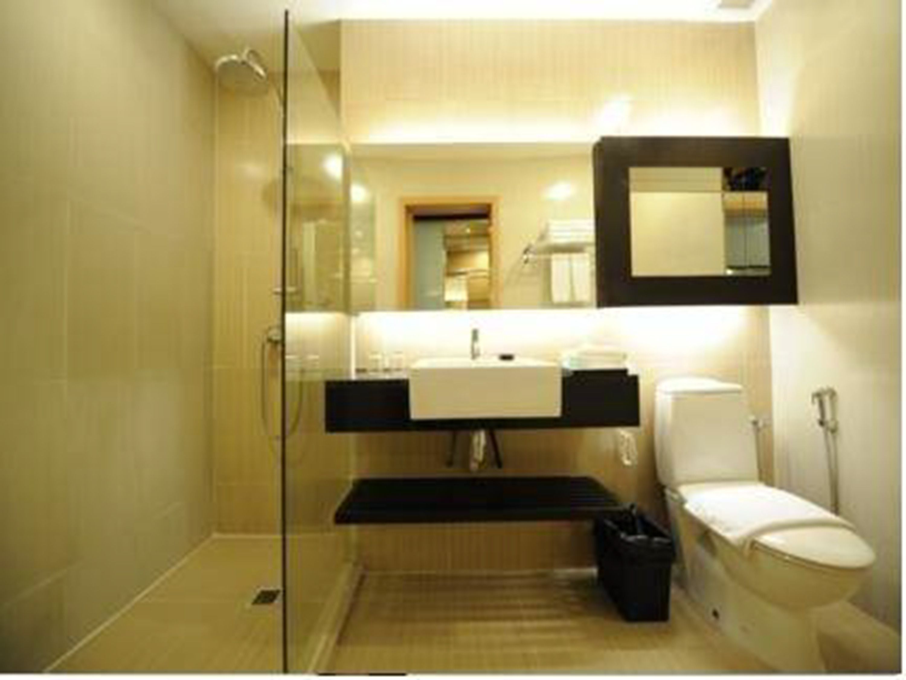 Een moderne badkamer met een douchecabine van glas, een witte wastafel en een toilet.