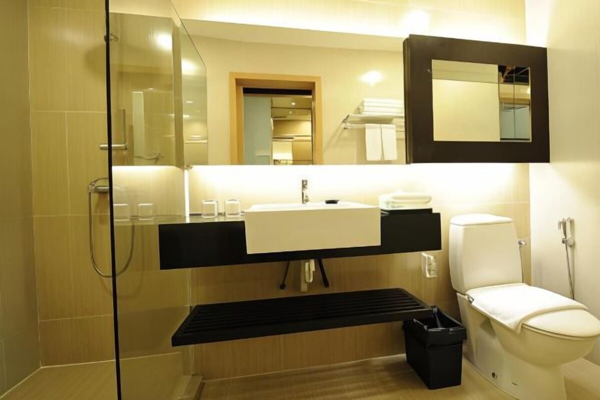 A modern bathroom with a glass shower enclosure, a white sink, a black vanity, and a toilet.
