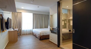 Ein Hotelzimmer mit Bett, Schreibtisch, Stuhl, Fernseher und einem Badezimmer mit Dusche und Badewanne.