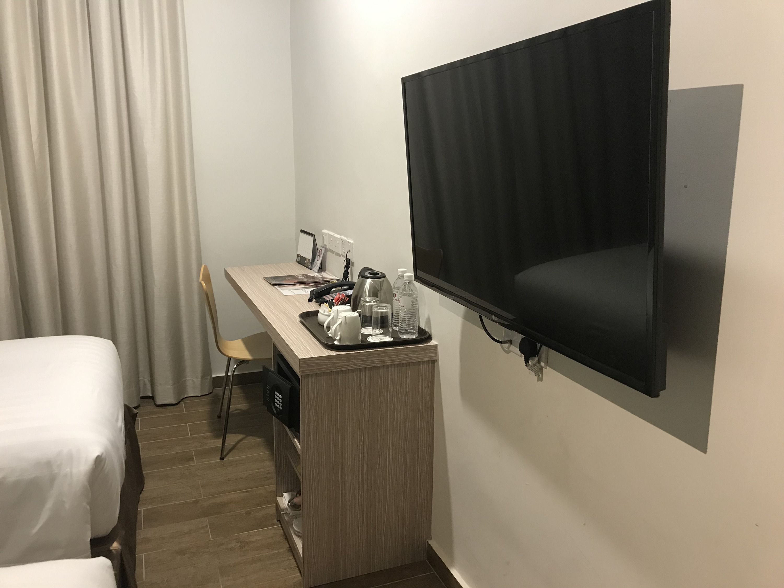 A hotel room with a bed, a desk with a TV, and a chair.