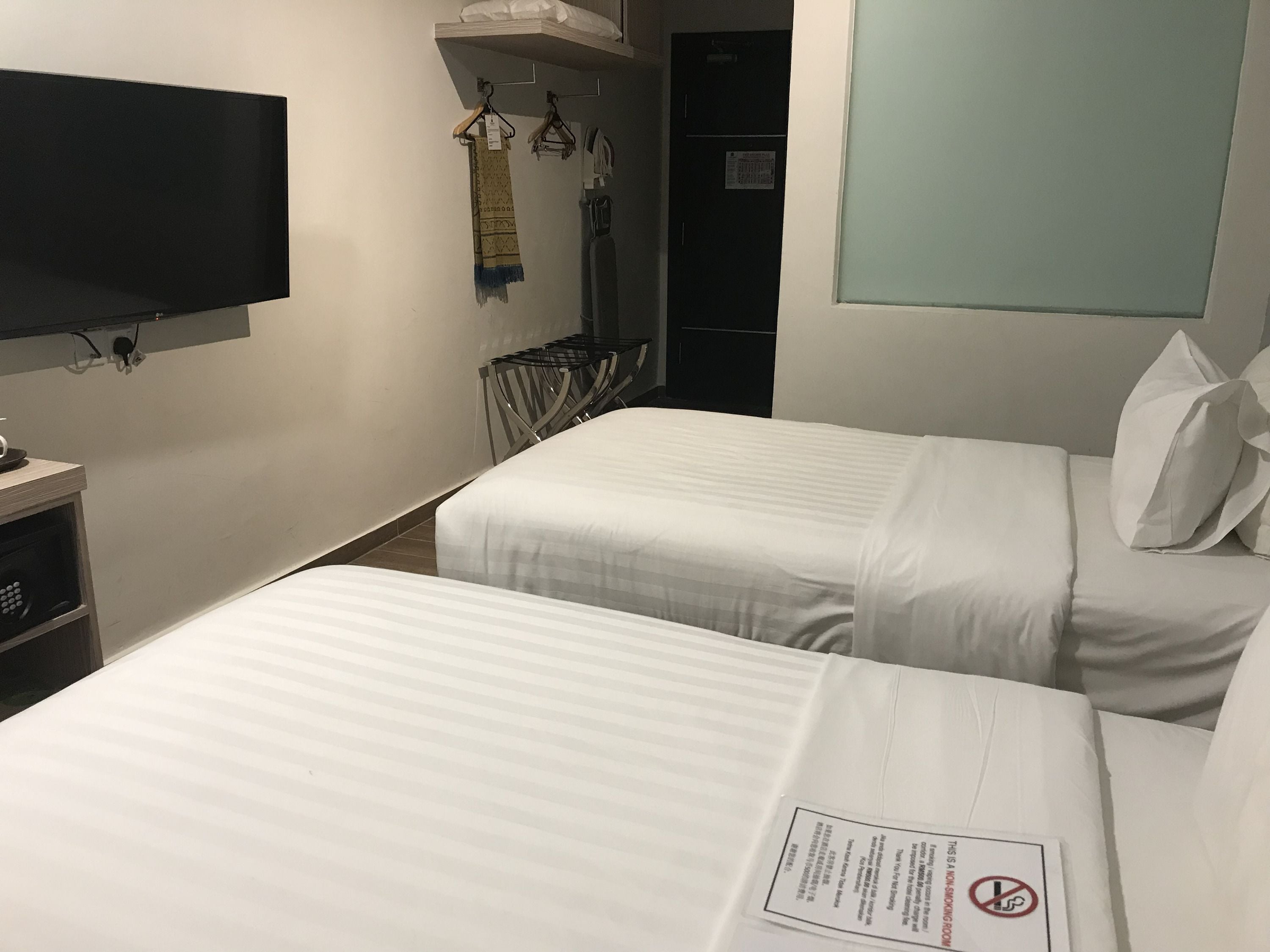 Une chambre d’hôtel avec deux lits, une télévision, un bureau avec un ordinateur et une armoire.