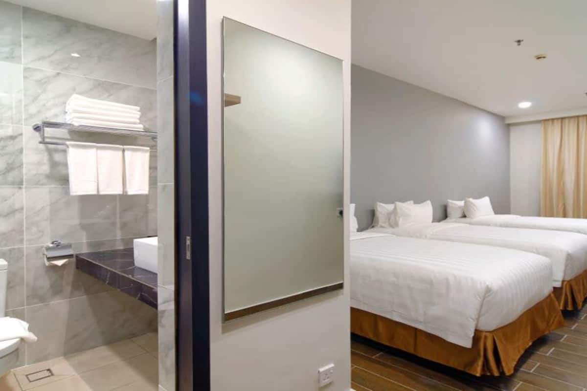 A hotel room with a marble bathroom, a large mirror, a bed with white bedding, and a wooden floor.