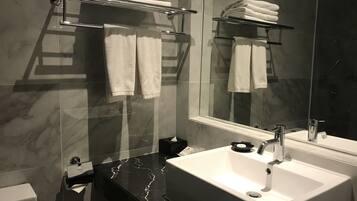A modern bathroom with a large mirror, a white sink, and two towel racks.