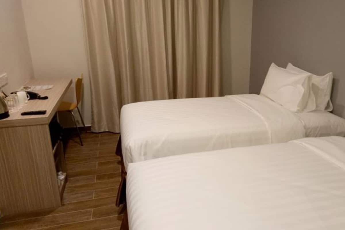 A hotel room with two beds, a desk, and a chair.