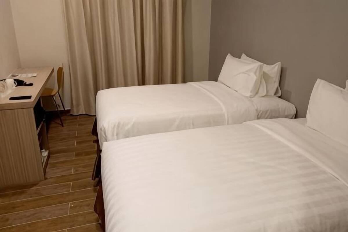 A hotel room with two beds, a desk, and a chair.