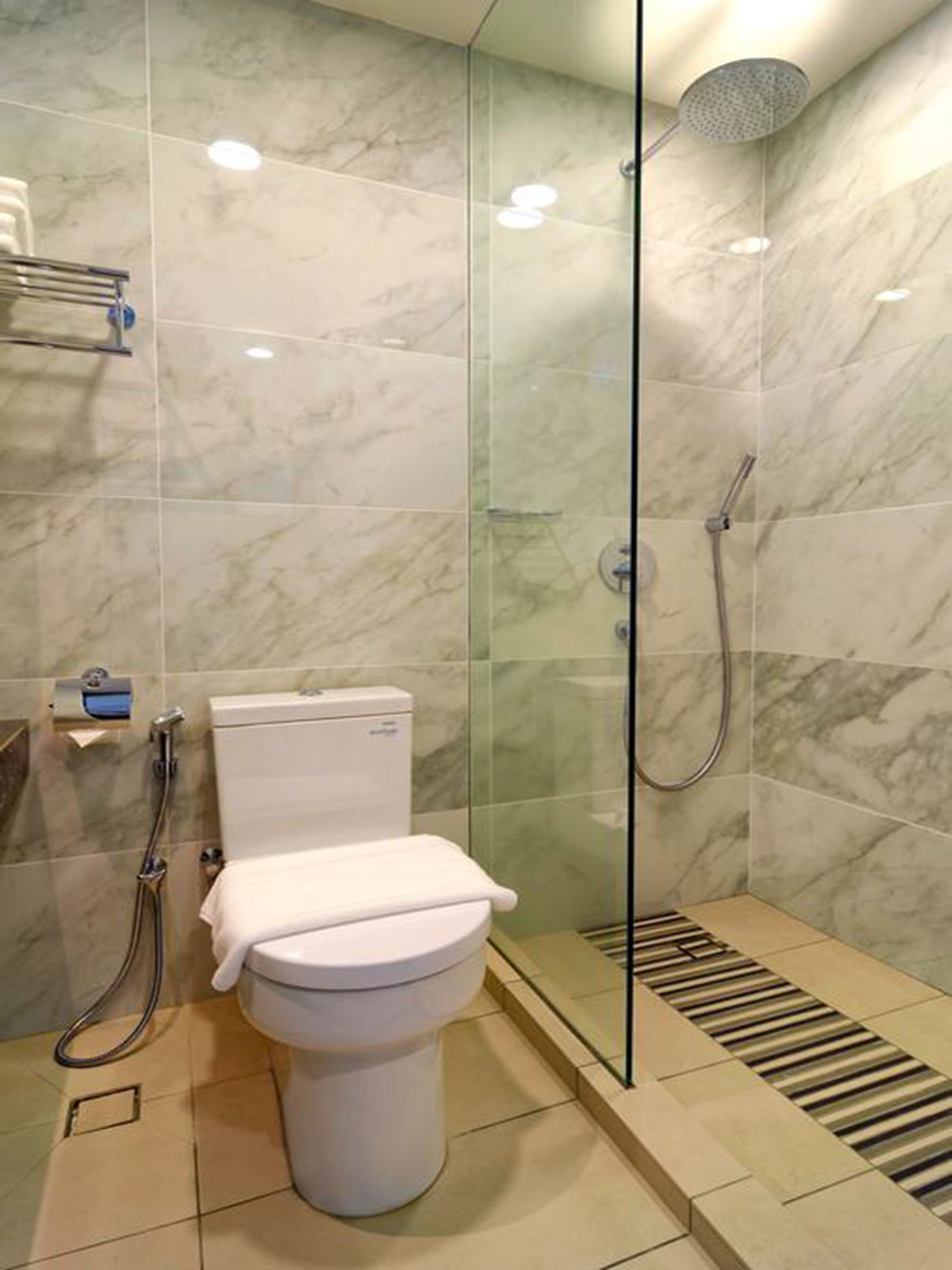 A modern bathroom with a toilet, shower, and glass-enclosed shower area.
