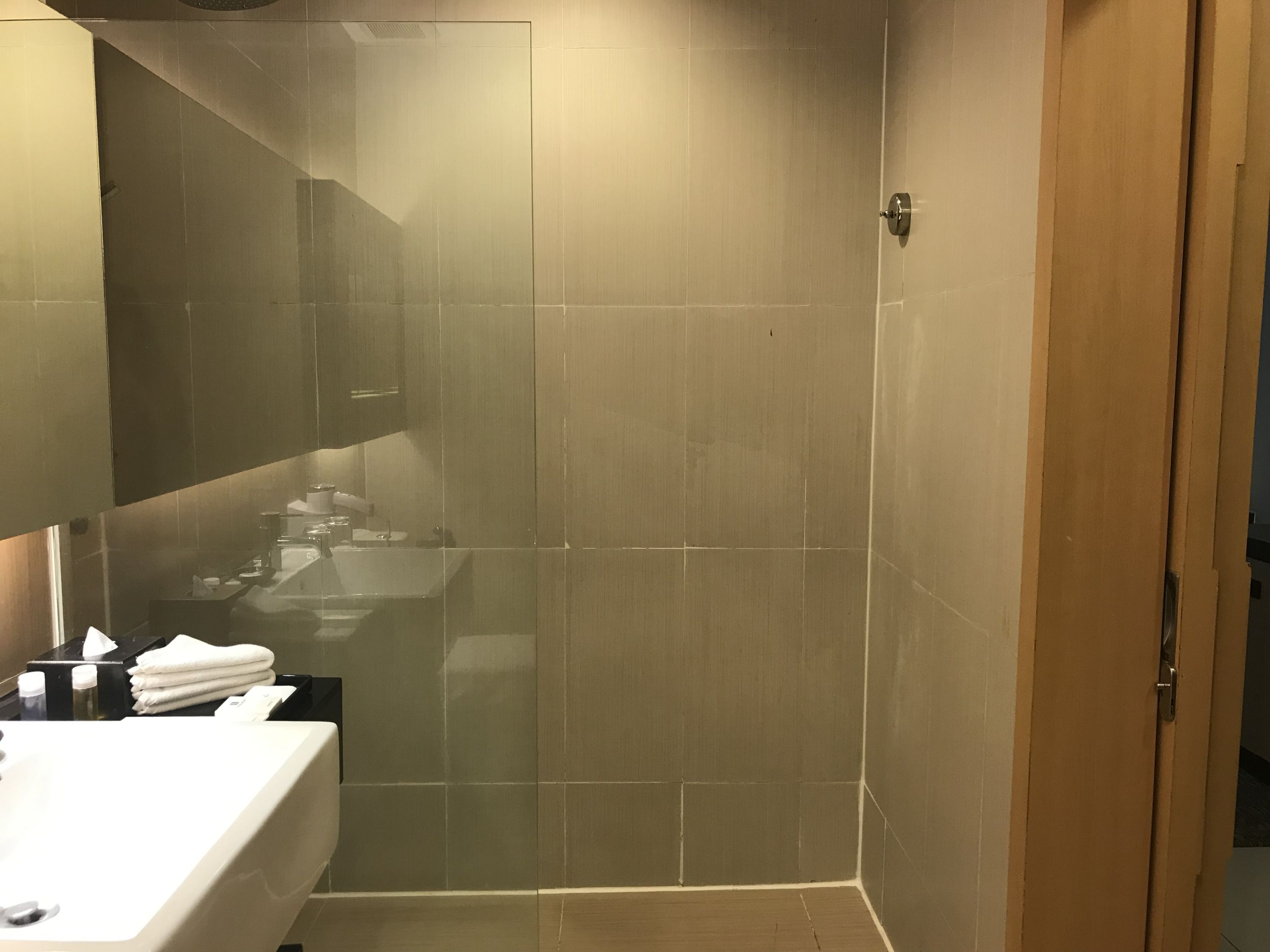Une salle de bain moderne avec une douche à parois de verre, un lavabo et un miroir.