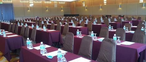A conference room with rows of tables, each with water bottles and nameplates.