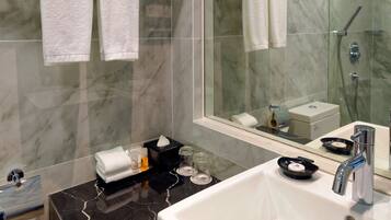 A modern bathroom with a large mirror, a white sink, and a glass-enclosed shower.