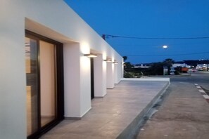 A modern building with a series of illuminated windows and a paved walkway. - Evita Elite (Rhodes)