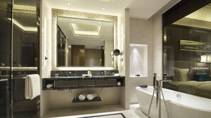 Un baño moderno con un espejo grande, lavamanos dobles, bañera y cabina de ducha con mampara de vidrio.