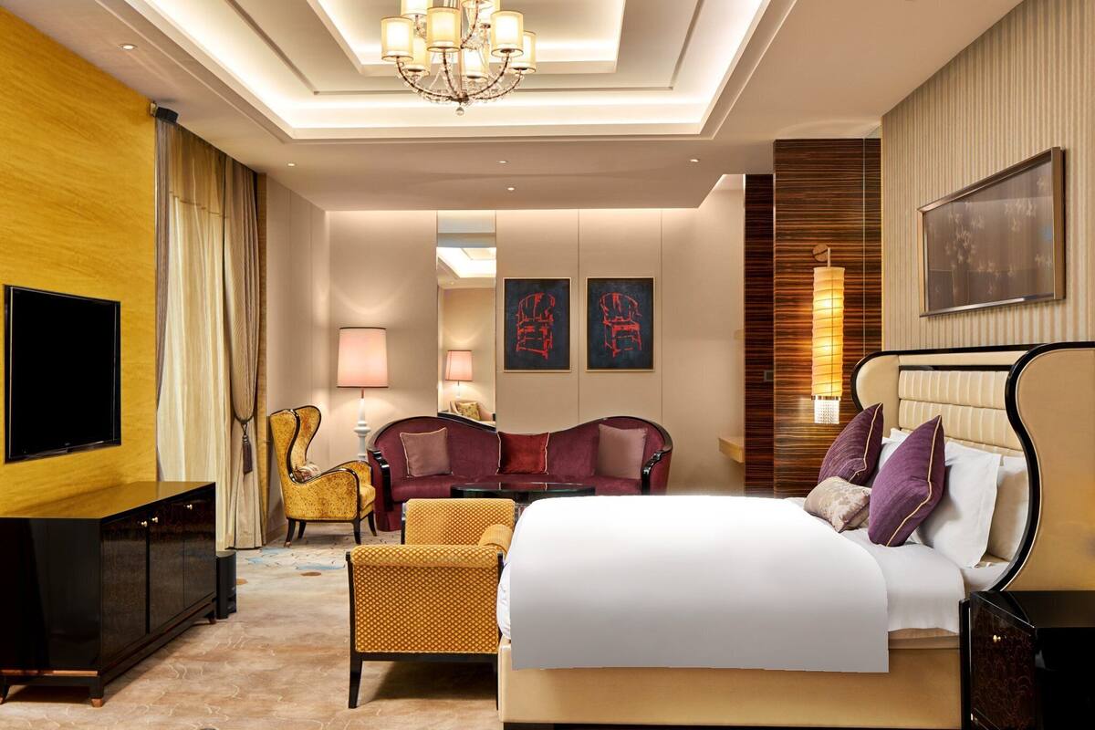 Una habitación de hotel con una cama grande, televisión, sofá y escritorio.