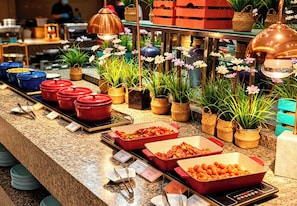 Ein reichhaltiges Buffet mit verschiedenen Speisen und dekorativen Pflanzen.