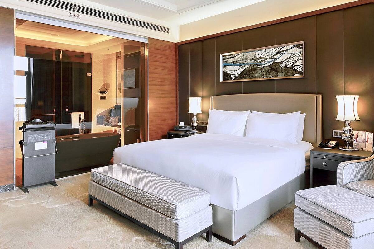 A hotel room with a large bed, a desk, a chair, and a bathroom.