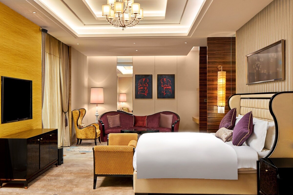 Una habitación de hotel con una cama grande, televisión, sofá y escritorio.