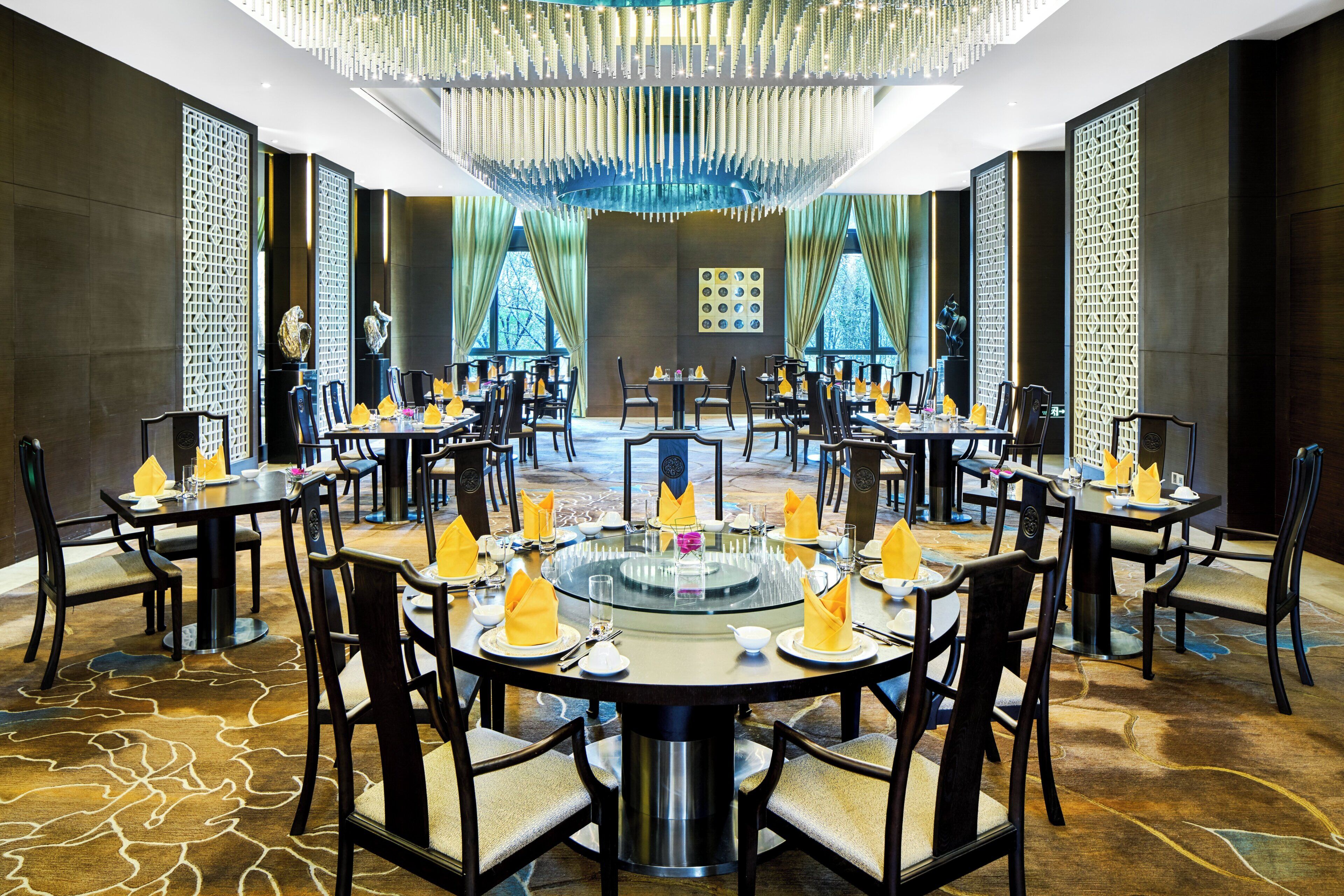 A formal dining room with round tables, chairs, and a central decorative feature.