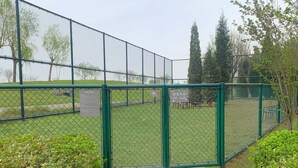 A fenced outdoor area with a paved entrance, surrounded by greenery and trees. - Crowne Plaza Tianjin Jinnan by IHG (Tianjin)