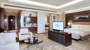 A hotel room with a bed, a TV, a seating area with a table, and a minibar. - Crowne Plaza Tianjin Jinnan by IHG (Tianjin)